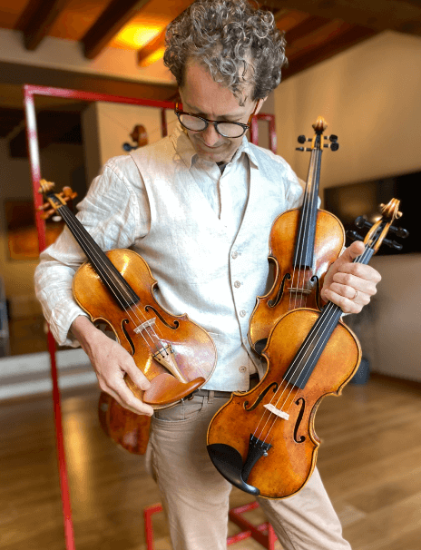 Violin Care luthier holding 3 violins